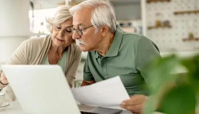 retirement-planning-financial-review Retired couple reviewing financial documents together on a laptop.