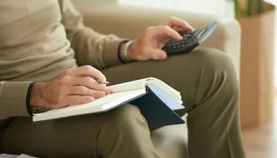 superannuation-fund-selection-review Person using a calculator and taking notes while comparing superannuation fund options.